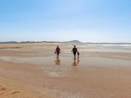 The persons walk at Valdovino Beach. Valdovino, Galicia, Spain photo