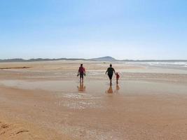 The persons walk at Valdovino Beach. Valdovino, Galicia, Spain photo