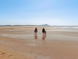 The persons walk at Valdovino Beach. Valdovino, Galicia, Spain photo