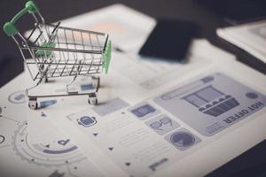 Analysis of online merchandising business reports, with charts and market statistics, shopping carts and promotional items. tabletop, ecommerce concept and online selling website photo