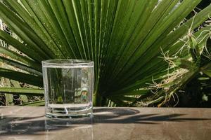 Water flows into a glass placed on a wooden bar photo