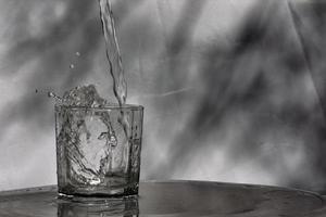 Water flows into a glass placed on a wooden bar photo