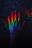 LGBT pride. Gay rights. Peace freedom. Diversity harmony. Graceful woman hands in blur rainbow lights. Iridescent blue red green yellow color gradient glow on dark empty space background. photo