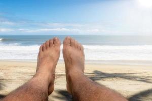 Feet man on the beach with the sea and blue sky in the background with copyspace photo