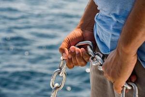 manos sosteniendo la cadena del ancla en el barco foto