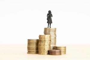 Wealth, making money, wage growth concept. Woman figurine standing on a pile of coins. Copy space photo