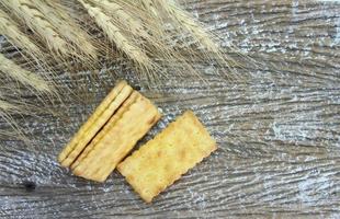 sandwich crackers with cream and barley plant on wood table photo