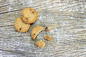 round chocolate chip cookie with crumbs on wood table background photo