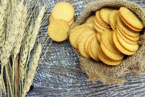 galletas cracker redondas en bolsa de saco con planta de cebada seca foto