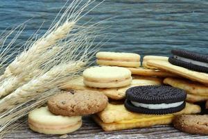 variedad de galletas de chocolate en mesa de madera. galletas con trocitos de chocolate rodadas con planta de cebada foto