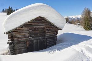 una cabaña de madera en el fondo de la nieve invernal foto