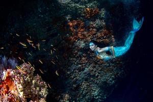 sirena nadando bajo el agua en el mar azul profundo foto