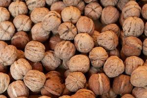 Texture with lots of walnuts, all lying next to each other with their shell still on. photo