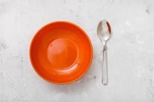 top view orange bowl and spoon on concrete plate photo