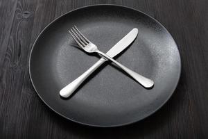 black plate with crossing knife, spoon on dark photo