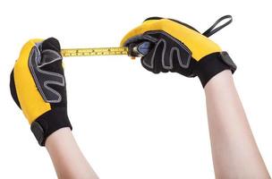 hands in protective gloves with tape measure photo
