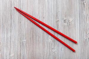 red wooden chopsticks on light brown wooden board photo