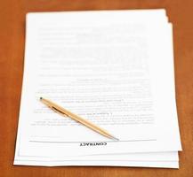 sales contract and golden pen on wooden table photo