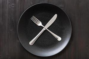 top view black plate with flatware on dark brown photo