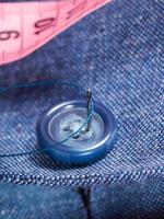attaching of button to blue silk suit by needle photo