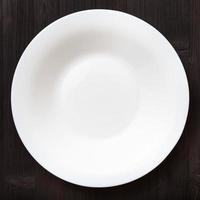 above view of white deep plate on dark brown table photo