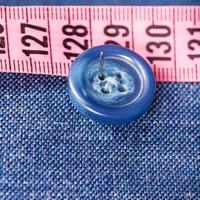 fijación del botón a la tela de seda azul con aguja foto