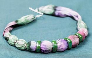 necklace from silk balls and ceramic ring on green photo