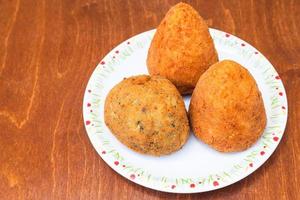 various rice balls arancini on plate on table photo