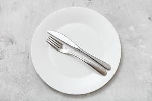 top view of white plate with flatware on concrete photo