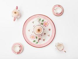 above view of pink porcelain tea set on white