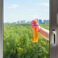 hand sprays liquid from spray bottle to window photo