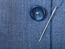 attaching of button to blue silk tissue by needle photo