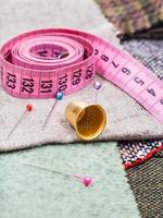 pink measuring tape, pins, thimble on tissue photo