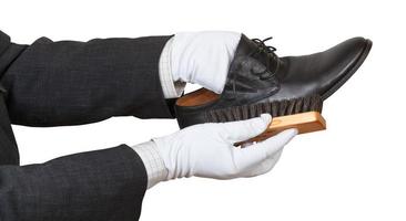 Shoeshiner in white gloves brushing black shoe photo