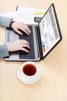 man reads business news from laptop at table photo