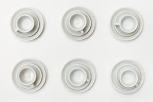 top view of six white cups and saucers on white photo