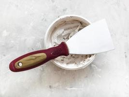 metal spatula on container with putty photo