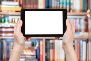 hands holding tablet pc in front of books photo