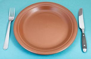 brown ceramic plate with fork and knife on green photo