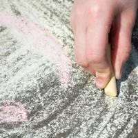 girl drawing with colored chalk on pavement photo