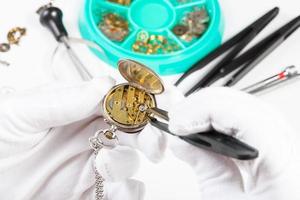 adjusting of brass pocket watch by tweezers photo