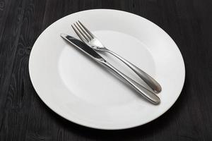 white plate with parallel knife, spoon on dark photo