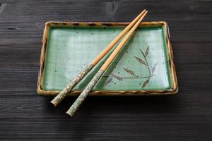 square plate with chopsticks on dark brown board photo