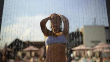 Young woman in swimsuit taking shower at water park video