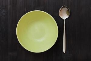 top view green bowl and spoon on dark brown table photo