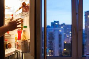 hand reaches to refrigerator and view of city photo