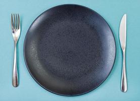 top view of black plate, fork, knife set on green photo