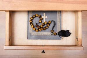 gemstone rosary on Bible book in open drawer photo