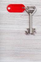 big key with red key chain on wooden surface photo