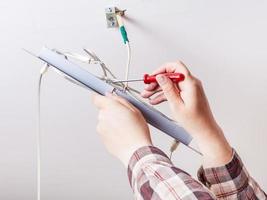 Electrician repairs wiring in ceiling lamp photo